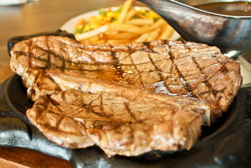 beef steak served on a hotplate along with french fries and sauce