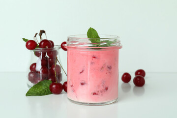 Glass jar of cherry smoothie and ingredients on white background