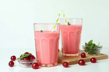 Glasses of cherry smoothie and ingredients on white table
