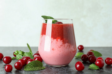 Glass of cherry smoothie and ingredients on black smokey table