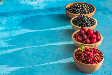 Fresh organic summer berries mix on blue concrete  background. Blueberries, red black currant and cherries. Top view. Concept of summer food. Flat lay, copy space
