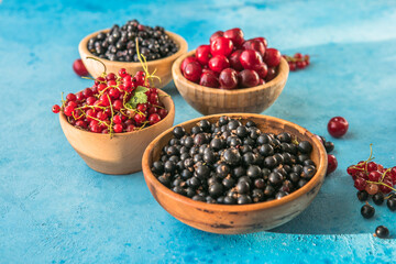 Fresh organic summer berries mix on blue concrete  background. Blueberries, red black currant and cherries. Top view. Concept of summer food. Flat lay, copy space