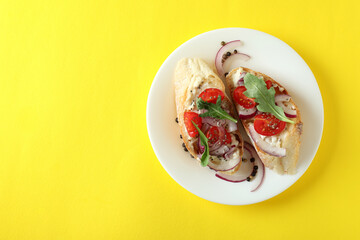 Plate with bruschetta snacks on yellow background