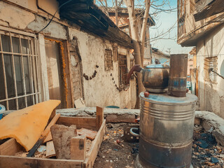Fototapeta na wymiar Blackened metal teapot on old samovar stove in the back streets of Ulus, Ankara. Tumbledown slums in an alley of Ulus district.