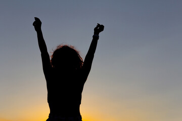 Woman with arms raised at sunset. Feeling of happiness and victory. Copy space.