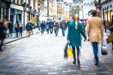 Motion blurred shopping couple walking on busy high street scene 