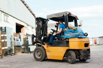 Fototapeta na wymiar Worker driving forklift and loading glass constructions