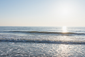 Naklejka na ściany i meble beautiful sunset or sunrise waves on the beach. blue sky and calm beach landscape.