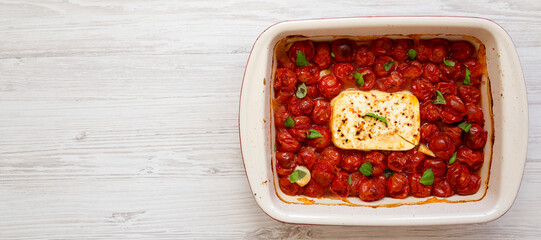 Homemade Baked Feta Tomato Pasta in a baking dish on a white wooden background, top view. Flat lay,...