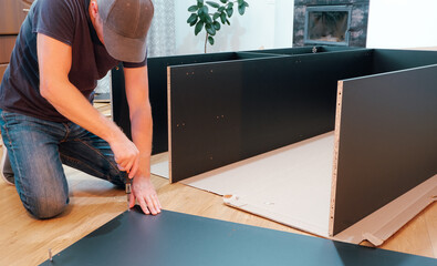 Furniture assembly workflow. A young man collects furniture brought from the store. Assembling the cabinet yourself.