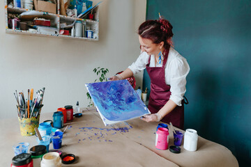 Artist mixing acryl paints on the picture working in fluid art technique