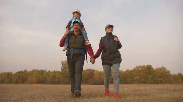 A happy family. A family of tourists walking together in the field. Family hike. Tourist group team work. Tourist lifestyle. Outdoor hiking. A helping hand on a hike.