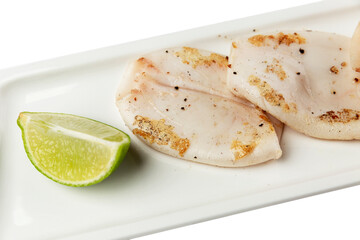 Fried squid carcasses with lemon on a white grater. Appetizing dietary Mediterranean food. Close-up.
