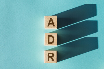 Wooden cubes building word ADR - adverse drug reaction, on light blue background.