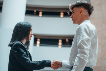 Muchacha joven realiza un apreton de manos con su cliente en su oficina