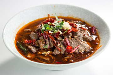 Chinese spicy soup with beef, vegetables and chili pepper isolated on white background