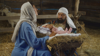 Mary and Joseph taking care of baby Jesus in inn stable