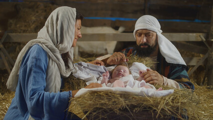Mary and Joseph taking care of baby Jesus in inn stable