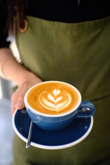 Barita hands holding a Latte art hot coffee drink