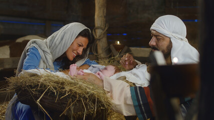 Mary and Joseph speaking with baby Jesus in manger