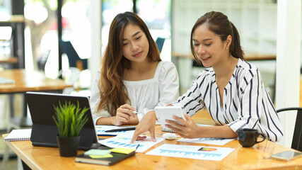 two casual asian businesswomen discussing work in office