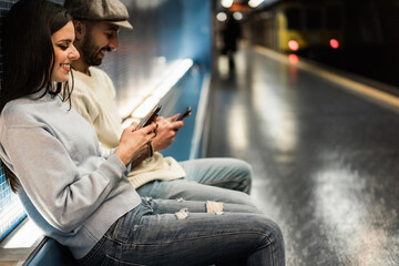 Young couple using mobile phones in subway underground - Focus on girl hands