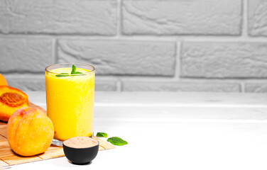 Smoothie with peach and mint leaf with piece of cloth on white brick background, Healthy summer diet