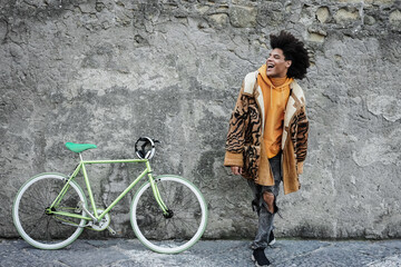 Young african boy having fun with his bicycle outdoor in the city - Fashion style photo - Focus on...