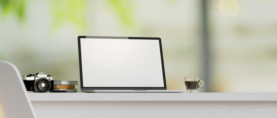 Laptop mockup with camera, books, coffee cup on table countertop with blurred background