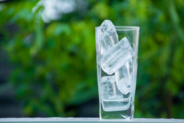 A glass of water full of ice. green blur background