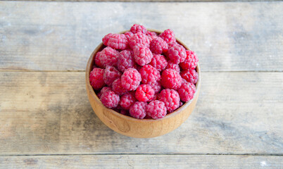 A bowl of raspberries on a wooden background.