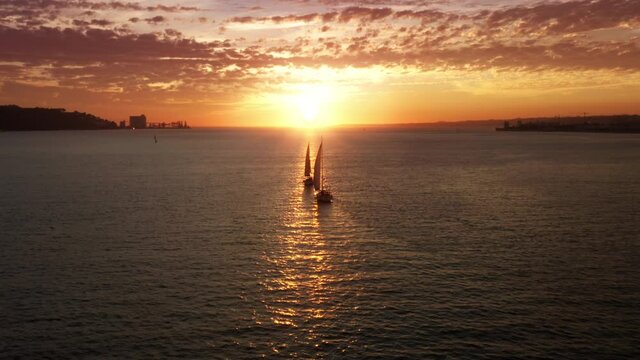 Lisbon, Portugal, Europe. Drone footage of sailing regatta with a cityscape in the background. Astonishing scenery of the yachts with sun setting behind. High quality 4k footage