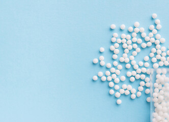 Homeopathy medicine alternative herbs. Homeopathic globules and glass bottle on a blue background. Health care and medicine concept.