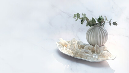 Quartz minerals and eucalyptus plant on marble background. gemstones crystals for healing esoteric...