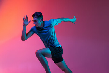 Portrat of Caucasian professional male athlete, runner training isolated on pink studio background...
