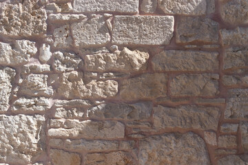Ancient wall made of stacking pieces of stone with a cast shadow.