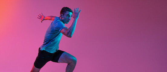 One Caucasian professional male athlete, runner training isolated on pink studio background with...