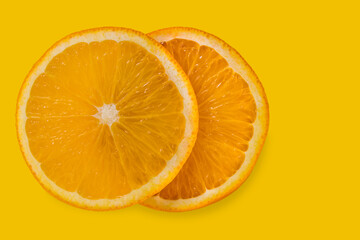 Two slices of orange isolated on yellow background with copy space