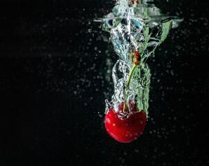 ripe cherries fall into the water raising splashes and air bubbles