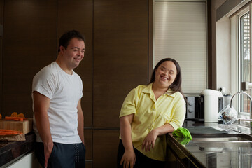 Young biracial couple with Down Syndrome laughing and being silly in the kitchen