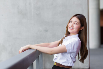 Portrait of an adult Thai student in university student uniform. Asian beautiful girl sitting smiling happily at university