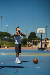 Chico joven atletico tatuado jugando a baloncesto en cancha azul