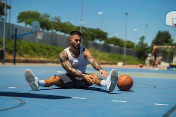 Chico joven atletico tatuado jugando a baloncesto en cancha azul