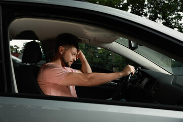 Obraz na płótnie Canvas Stressed man in driver's seat of modern car