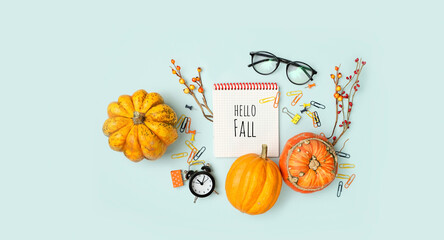 notepad, pumpkins, alarm clock, eyeglasses on blue background. Hello Fall. autumn season concept....