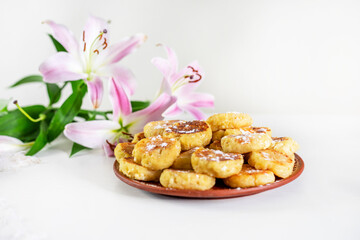 good morning, breakfast with cheesecakes and pink lilies on a white table lit by the sun, horizontal,