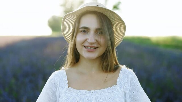 Nice young Caucasian woman portrait wearing summer dress looking at camera. Girl in hat. Outdoors. Summertime. Cute Girl Smiling Face.