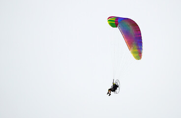 Paragliding with a motorized paraglider. Colorful paraglider in flight.