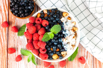 Bowl of granola with rip raspberries, blueberries and yoghurt on a wooden background. Healthy and tasty breakfast in the morning. ?lose-up. Top view.