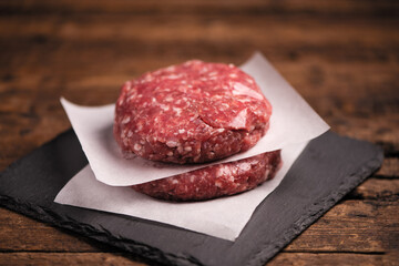 Raw ground beef meat burger steak cutlets on wooden background